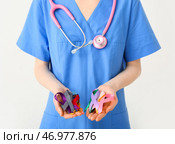 Женщина-врач держит различные ленты осведомленности на белом фоне. Всемирный день борьбы против рака. Стоковое фото, фотограф Pixel_shot / Фотобанк Лори