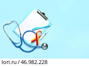 Лента осведомленности со стетоскопом, шприцем, ручкой и буфером обмена на синем фоне. Концепция гепатита. Стоковое фото, фотограф Pixel_shot / Фотобанк Лори