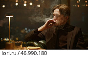 Attractive young man smokes cigar cinematically. Стоковое фото, фотограф David Kashakhi / Фотобанк Лори