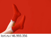 Ноги молодой женщины в теплых вязанных носках на красном фоне. Стоковое фото, фотограф Pixel_shot / Фотобанк Лори