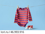 Детские ботинки и боди висят на веревке на фоне цветного фона. Стоковое фото, фотограф Pixel_shot / Фотобанк Лори