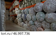 Young man passing by a stack of rolls of fabric lies in the warehouse of a garment factory. Стоковое фото, фотограф David Kashakhi / Фотобанк Лори