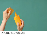 Женская рука с бутылочкой крема для солнцезащиты на зеленом фоне. Стоковое фото, фотограф Pixel_shot / Фотобанк Лори