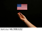 Женщина держит горящую свечу с флагом США на черном фоне. Национальный день молитвы и воспоминания о жертвах террористических атак. Стоковое фото, фотограф Pixel_shot / Фотобанк Лори