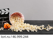Перевернутый ведро с попкорном, Хэллоуинской тыквой и кинематографической щитовидной доской на деревянном столе на сером фоне. Стоковое фото, фотограф Pixel_shot / Фотобанк Лори
