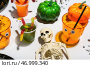Накрытый стол для Хэллоуина с пуншем, скелетом и мармеладными червями на белом фоне. Стоковое фото, фотограф Pixel_shot / Фотобанк Лори