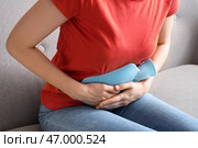 Молодая женщина с грелкой для живота страдает от боли в животе дома, крупным планом. Стоковое фото, фотограф Pixel_shot / Фотобанк Лори
