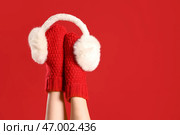 Женщина в теплых носках с ушными муфтами на красном фоне. Стоковое фото, фотограф Pixel_shot / Фотобанк Лори