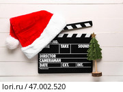 Штатив для киносъемки с шапкой Санты и украшенной рождественской елкой на белом деревянном фоне. Стоковое фото, фотограф Pixel_shot / Фотобанк Лори