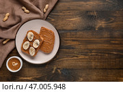 Тарелка с тостами с арахисовым маслом, бананом и маковыми семечками на деревянном фоне. Стоковое фото, фотограф Pixel_shot / Фотобанк Лори