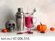 Стакан вкусного розового коктейля, шейкер, череп и сладкие насекомые для Хэллоуинского празднования на светлом фоне. Стоковое фото, фотограф Pixel_shot / Фотобанк Лори