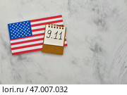 Флаг США и блокнот с датой Национального дня молитвы и памяти жертв террористических атак на грунтовом белом фоне. Стоковое фото, фотограф Pixel_shot / Фотобанк Лори