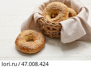 Плетёная корзина с вкусными бубликами с кунжутом на белом деревянном фоне. Стоковое фото, фотограф Pixel_shot / Фотобанк Лори