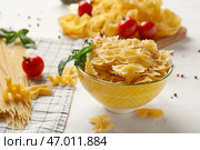 Миска с сырыми фарфалле и специями на светлом фоне, крупным планом. Стоковое фото, фотограф Pixel_shot / Фотобанк Лори