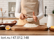 Женщина просеивает муку для приготовления теста на кухонном столе. Стоковое фото, фотограф Pixel_shot / Фотобанк Лори