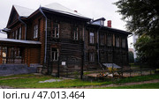 A large two-storey house made of wood standing without light on the background of a park where citizens walk. Стоковое фото, фотограф David Kashakhi / Фотобанк Лори