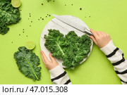 Женские руки с белой деревянной доской, свежими листьями капусты кале и ножом на зеленом фоне. Стоковое фото, фотограф Pixel_shot / Фотобанк Лори