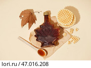 Вафли, бутылка и ложка вкусного кленового сиропа на бежевом фоне. Стоковое фото, фотограф Pixel_shot / Фотобанк Лори