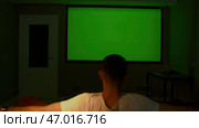 A man looking into a green screen that is shown on a large screen. Стоковая иллюстрация, иллюстратор David Kashakhi / Фотобанк Лори