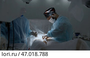 Specialists perform an operation, using medical instruments in operating room. Стоковое фото, фотограф David Kashakhi / Фотобанк Лори