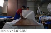 Germany - Berlin, May 20, 2023: Workers of the woodworking factory packing a wooden panel. Редакционное фото, фотограф David Kashakhi / Фотобанк Лори