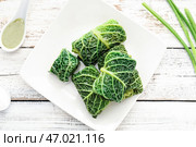 Тарелка с голубцами и соусом на светлом деревянном фоне. Стоковое фото, фотограф Pixel_shot / Фотобанк Лори