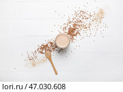 Стакан вкусного гречневого молока и ложка на светлом фоне. Стоковое фото, фотограф Pixel_shot / Фотобанк Лори