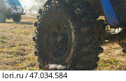 A close-up of a large, muddy off-road tire with a deep tread pattern. Other off-road vehicles are visible in the background. Extreme off-roading competition. Стоковое фото, фотограф Воловодов Владимир / Фотобанк Лори
