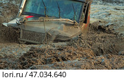 A close-up of a muddy off-road vehicle driving through a deep muddy puddle. A plow or an anchor for a winch is attached to the hood of the car. Extreme off-road competitions. Стоковое фото, фотограф Воловодов Владимир / Фотобанк Лори