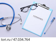 Буфер обмена со словом HORMONES, стетоскоп и очки на сером фоне. Стоковое фото, фотограф Pixel_shot / Фотобанк Лори