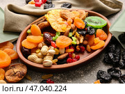 Тарелка и пакеты с разными сухофруктами и орехами на сером фоне. Стоковое фото, фотограф Pixel_shot / Фотобанк Лори