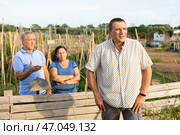 Disgruntled aged couple talking to man near wooden fence of rural house. Стоковое фото, фотограф Яков Филимонов / Фотобанк Лори