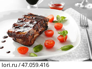 Вкусные жареные ребрышки с соусом и помидорами на тарелке, крупным планом. Стоковое фото, фотограф Pixel_shot / Фотобанк Лори
