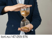 Женщина, держащая песочные часы с песком на сером фоне. Концепция тайм-менеджмента. Стоковое фото, фотограф Pixel_shot / Фотобанк Лори