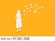Бумажная женская фигура с гормональными таблетками на оранжевом фоне. Стоковое фото, фотограф Pixel_shot / Фотобанк Лори