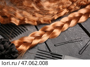 Рыжие волосы со скрученными резинками, щетками и заколками на темном деревянном фоне, крупным планом. Стоковое фото, фотограф Pixel_shot / Фотобанк Лори