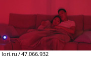 Couple watching movie on sofa under blanket with projector. Стоковое видео, видеограф Константин Шишкин / Фотобанк Лори