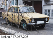 IZH 412 car is parked in the courtyard of the house. An old beige or yellow Moskvitch car is parked on the street. Редакционное фото, фотограф Константин Григорьев / Фотобанк Лори