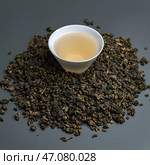 Delight in Oolong Tea Leaves accompanied by a perfectly Brewed Cup for ultimate enjoyment. Стоковое фото, фотограф David Kashakhi / Фотобанк Лори