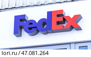 Вывеска с логотипом FedEx. Американская многонациональная компания экспресс-доставки Federal Express (2022 год). Редакционное фото, фотограф FotograFF / Фотобанк Лори