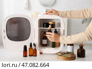 Женские руки достают эфирное масло из маленького косметического холодильника на столе на фоне белого фона. Крупный план. Стоковое фото, фотограф Pixel_shot / Фотобанк Лори