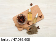 Бутылки с эфирным маслом с анисовыми звёздами, сушёными семенами и ложкой на белом деревянном фоне. Стоковое фото, фотограф Pixel_shot / Фотобанк Лори