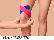 Физиотерапевт накладывает пластырь на колено женщины на цветном фоне, крупный план. Стоковое фото, фотограф Pixel_shot / Фотобанк Лори