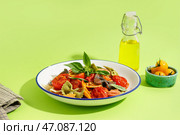 Миска вкусной пасты фарфалле с томатами и базиликом на зеленом фоне. Стоковое фото, фотограф Pixel_shot / Фотобанк Лори