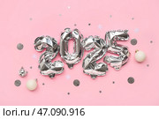 Фигура 2025 из фольгированных шаров с рождественскими шарами и конфетти на розовом фоне. Стоковое фото, фотограф Pixel_shot / Фотобанк Лори