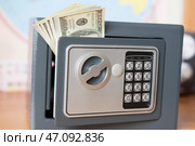 Денежные купюры торчат из приоткрытой дверки небольшого домашнего сейфа. Стоковое фото, фотограф Дмитрий Сакретарев / Фотобанк Лори