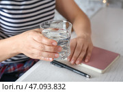 Женщина со стаканом пресной воды за столом, крупным планом. Стоковое фото, фотограф Pixel_shot / Фотобанк Лори