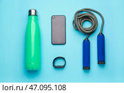 Спортивная бутылка с водой, мобильный телефон, фитнес-трекер и скакалка на цветном фоне. Стоковое фото, фотограф Pixel_shot / Фотобанк Лори