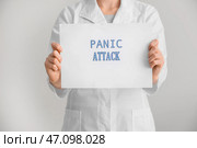 Женщина-врач держит бумагу с текстом ПАНИЧЕСКАЯ АТАКА на белом фоне. Стоковое фото, фотограф Pixel_shot / Фотобанк Лори