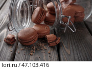 Стеклянная банка и вкусные шоколадные макаруны на столе. Стоковое фото, фотограф Pixel_shot / Фотобанк Лори